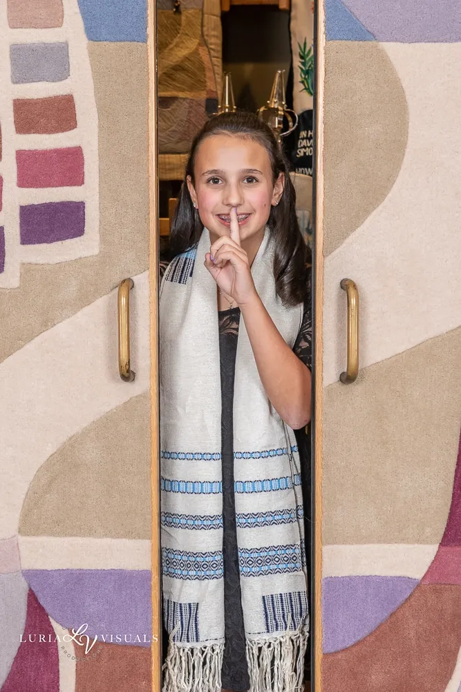 Bat mitzvah girl peeking out from behind her tallit