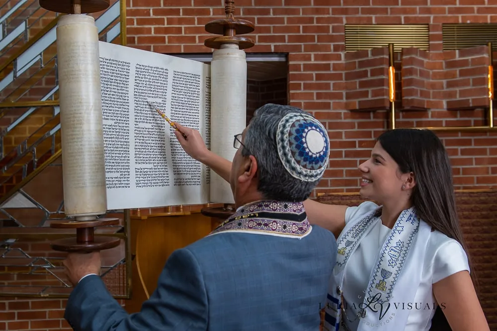 Father guiding his daughter through the Torah reading