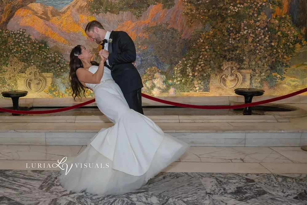 Groom dipping the bride for a kiss beneath a painted mural