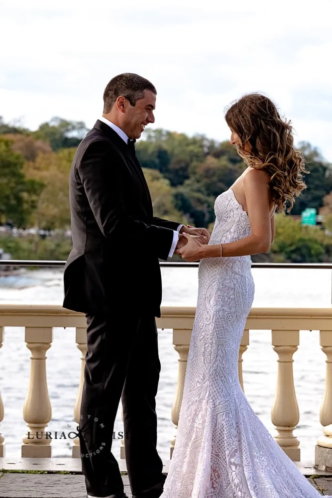 Bride and groom holding hands on a waterfront terrace